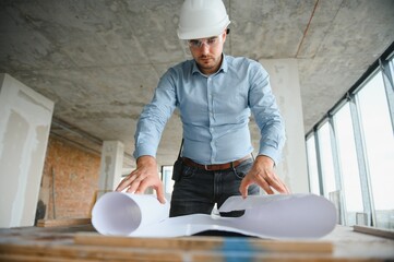 With plan in hands. Man in uniform is working on the construction site