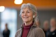 © Joaquin Corbalan - A smiling woman using a hearing aid during a group activity in a modern community space, showcasing inclusivity and connection among participants