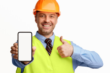 Poster - Construction Worker Showing Smartphone Empty Screen Gesturing Thumbs-Up, Recommending Architectural And Building Services On White Background. Selective Focus