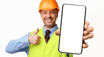 Poster - Construction Worker Showing Smartphone Empty Screen Gesturing Thumbs-Up, Recommending Architectural And Building Services On White Background. Selective Focus