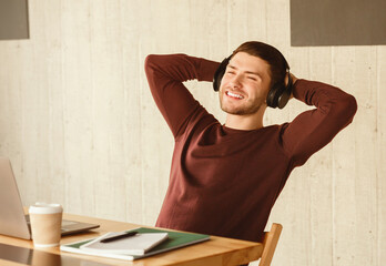 Poster - Freelance Guy In Headphones Procrastinating At Laptop Relaxing Sitting In Modern Office. Freelancer's Lifestyle