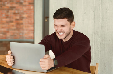 Poster - Stressful Job. Mad Office Guy Breaking Laptop Computer Sitting At Workplace Indoor. Selective Focus