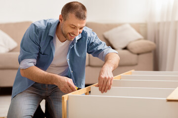 Aufkleber - Furniture Repair. Happy Man Fixing Cabinet Using Screwdriver Making Renovation Sitting On Floor At Home. Selective Focus