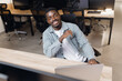 © Parilov - African american man in modern office setting, symbolizing business success and innovation. seated confidently at desk with open laptop, embodying professional growth and opportunity.