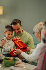 Wall Mural - Happy family opening gifts together around a festive table