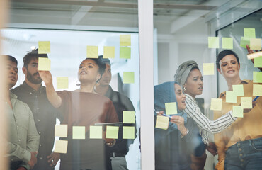 Business people, schedule or planning with glass board for meeting, collaboration or brainstorming at office. Young, group or employees writing with teamwork for agenda, tasks or reminder for project