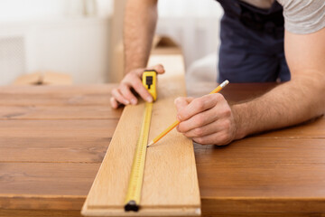 Fototapete - Carpentry Career Concept. Unrecognizable Carpenter Measuring Wooden Board Making A Piece Of Furniture Working In His Studio. Cropped Shot, Selective Focus
