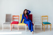 © dmitriisimakov - Brunette woman and many chairs in a white room