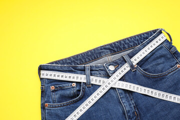 Poster - Jeans and measuring tape on yellow background, top view. Space for text