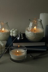 Poster - Beautiful burning candles, books, candle snuffer and wick trimmer on gray background, closeup