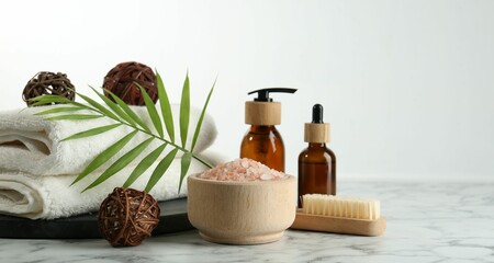 Poster - Spa treatment. Towels, sea salt, brush, bottles of cosmetic products and palm leaf on white marble table, space for text