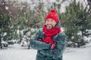 Portrait of satisfied glad person toothy smile crossed arms wear red knitted scarf headwear snowy woods outside