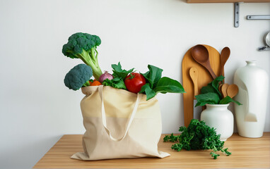 Fabric bag, shopper with fresh vegetables and herbs on a wooden tabletop in a light kitchen. Ecological and healthy food, life without garbage.