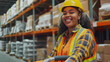© DigitaArt.Creative - a smiling woman in a warehouse setting, dressed in a bright orange safety vest and a yellow hard hat.