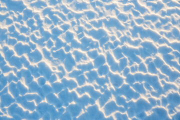 Wall Mural - beautiful winter background with snowy ground. natural snow texture. wind sculpted patterns on snow 