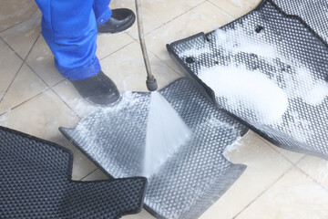 Poster - Man washing rubber car mats with high pressure water jet indoors, closeup