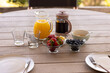 © Wavebreak Media - Breakfast table with fresh fruit, orange juice, and coffee on wooden patio