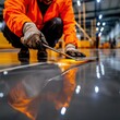 © Chopang.studio - Worker smoothing out a concrete floor with a trowel in a modern industrial setting.