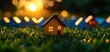 © Moonroad - Miniature house model with glowing windows on grass during sunset