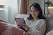 © Isuru - Happy woman using tablet on sofa  Asian beauty  empty screen.
