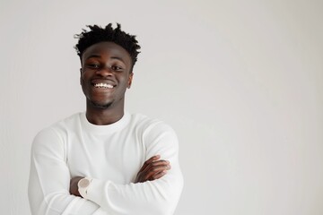 Portrait of stylish young black guy standing with arms crossed and laughing against white background