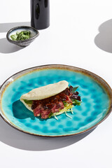 Wall Mural - Bao Bun with Marbled Beef on Vibrant Plate Minimal Still Life in Natural Light