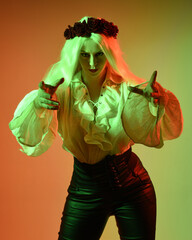 Canvas Print - close up portrait of  blonde female model, wearing vintage gothic fantasy ruffle blouse white shirt, leather pants. gestural pose with hands reaching out casting a spell. colourful studio lighting