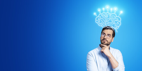 Poster - Portrait of attractive thoughtful young european businessman with glowing brain with lamps sketched hologram on blue background with mock up place. Idea, innovation and brainstorm concept.