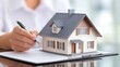 © MindVerse - Minimal small design of a house with a man in defocused background writing with his pen and hands in picture, real estate agent working, buying assets and housing