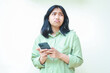 © M Alfan Setyawan - portrait of unhappy asian woman wearing over size green clothes look away showing sad gloomy face expression confused using smartphone apps and online shopping isolated on white background