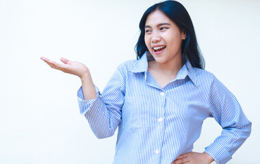 excited asian woman wearing blue striped shirt pointing to empty space standing over isolated background, carefree female introducing product