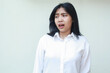© M Alfan Setyawan - surprised asian young business woman wearing white formal suit shirt shocked looking away down with open mouth, standing scared and afraid, frighten of trauma face expression, stressed of work time