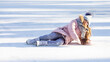 © Irina Mikhailichenko - Cute little girl in warm pink coat, grey knitted hat and scarf, snood lying on ice skating rink in park while learning to skate and falling down. Winter outdoor sport. Holiday and seasonal concept.