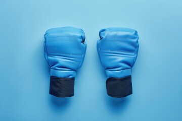 Blue boxing gloves arranged on a solid blue background for a sports concept