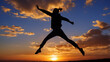 © AltisArt - Silhouette of a person jumping in the air with arms outstretched against a vibrant sunset sky, symbolizing freedom and joy.