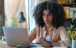 © ADDICTIVE STOCK CORE - Young woman working attentively on laptop at home office