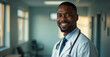 © Julia - Friendly adult male doctor in workwear with stethoscope on neck in clinic interior, looking and smiling at camera, copy space