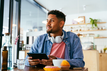 Handsome young hispanic man sitting in a bar cafeteria -  heerful african-american male relaxing in a pastry bakery coffee shop