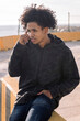 © Raul Mellado - african american male teenager talking on mobile phone sitting on urban street, concept of technology of communication and young lifestyle