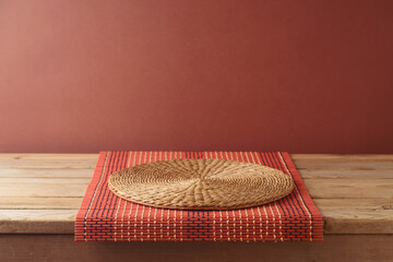 Canvas Print - Empty wooden table with bamboo tablecloth and place mat over brown wall background.  Kitchen mock up for design and product display