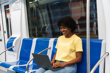 African American young woman using her laptop while riding the subway