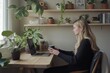 © felix_brönnimann - Woman working on a laptop at a cozy desk surrounded by indoor plants, enjoying a warm beverage in a serene home office environment.