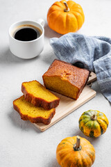 Wall Mural - Pumpkin sweet bread  on a wooden board on a light  background with decorative pumpkins and a cup of  coffee.