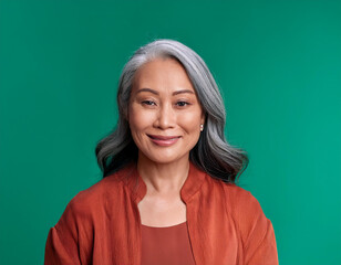 Wall Mural - Studio Portrait of Mature Teacher Woman Happily Smiling Against Colored Studio Background