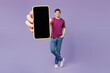 © ViDi Studio - Full body young man wear violet t-shirt casual clothes hold in hand use close up mobile cell phone with blank screen workspace area isolated on plain pastel light purple background. Lifestyle concept.