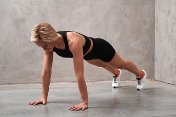 Fitness woman doing plank exercise workout in gym indoors. Straight arm plank exercise to strengthen the cortex. Fitness, sports, healthy lifestyle.