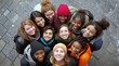 © David Giraud - Un groupe de jeunes gens souriants, représentant diverses ethnies et groupes d'âge, regardant vers l'objectif, vue de dessus.