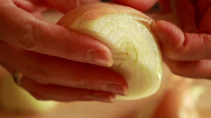 Wall Mural - woman's hands skillfully peeling a yellow onion