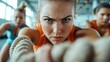 © Maximages  - A determined woman in athletic wear intensely pulling ropes during a vigorous gym session, depicting strength, focus, and perseverance in physical fitness activities.