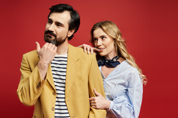 A middle aged couple showcases playful interaction while dressed in fashionable clothing.